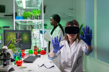 Researcher with virtual reality headset researching new genetic experiment for microbiology...