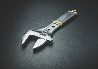 Adjustable wrench on black background.