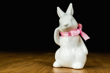 Porcelain toy bunny, Easter decoration on wooden table.