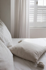 Fototapeta na wymiar White themed bed sheets and white curtain, bedroom interior.