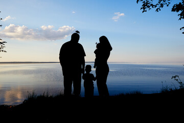 family silhouettes on the background of the evening sunset