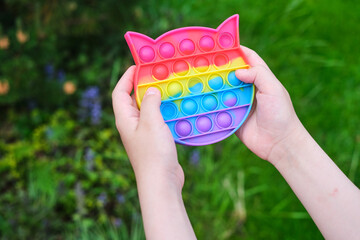 New popular silicone popit toy, baby is playing with it. Rainbow Trendy Pop it fidget toy.