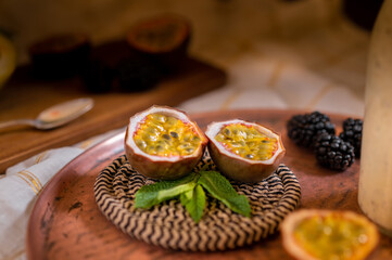 Dark moody food photography closeup of a maracuya passion fruit with blackberries. Natural and healthy food concept.