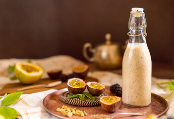 Dark moody food photography of a passion fruit smoothie bottle with blackberries. Natural and healthy drink concept.