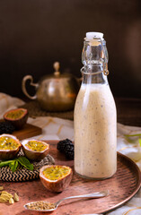 Food photography of a passion fruit smoothie bottle with blackberries. Natural and healthy drink concept.