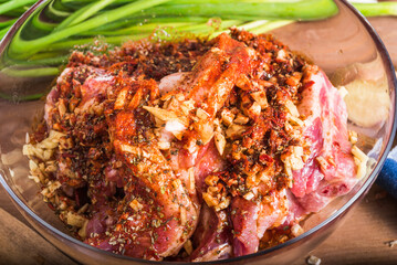 Cooking spicy pork. Chopped pork belly in a bowl with hot pepper, garlic and ginger sauce - oriental, chinese and korean cuisine. Marinated pork close-up.