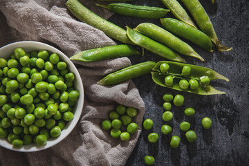 green peeled peas in a bowl on black background
