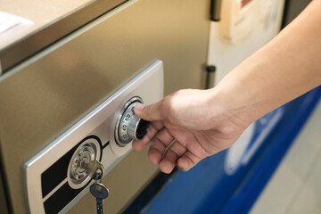 Close up of a hand unlocking a safe deposit box by turning a knob with numbers. Composite image between a hand photography 