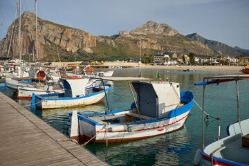 Fototapeta na wymiar typical Mediterranean colored wooden fishing boats moored at the port of an island with clear and clean sea in Sicily in San Vito lo Capo in the Province of Trapani
