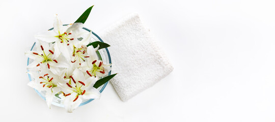 Transparent vase with water and white lilies with a white towel. Isolated on white. Spa concept for cleanliness, freshness and aromatherapy.