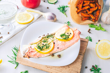 Baked salmon on a bright background. Salmon with vegetable side dishes.

