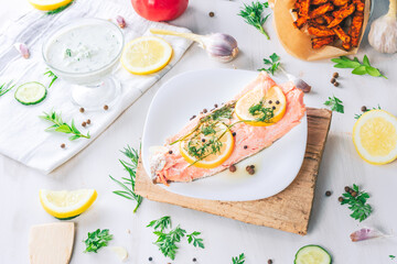 Baked salmon on a bright background. Salmon with vegetable side dishes.
