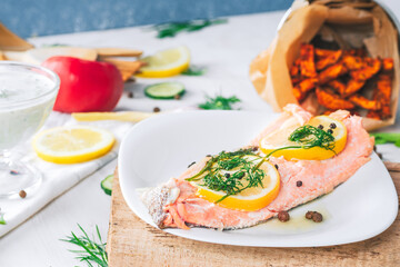 Baked salmon on a bright background. Salmon with vegetable side dishes.
