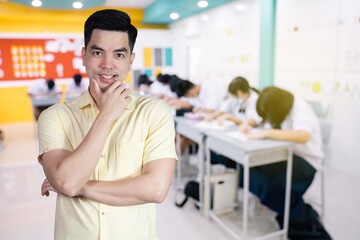 Obraz premium Portrait handsome young asian man wearing a yellow shirt happy smile isolated on background blurred student study in class at school. Education concept.