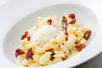 potato dumplings called halusky with dry tomatoes and grated cheese