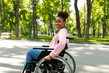 Positive handicapped black lady in wheelchair enjoying wonderful summer morning outdoors