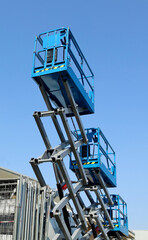 Fototapeta premium Three working platforms, called scissor elevator, against blue sky