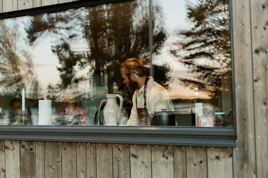 Man wearing apron in kitchen seen through window