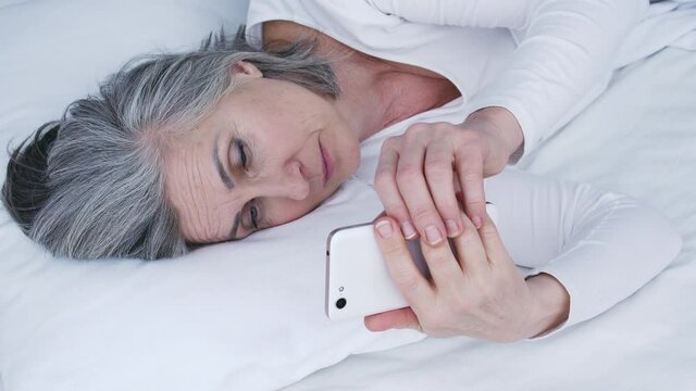 Lonely sad woman lying bed looking at photos of beloved or family, missing them