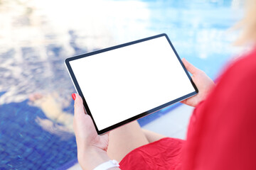 Young woman holding digital tablet with blank screen by pool