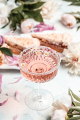 Rose wine in glass and peony flowers over white background, Summer celebration, wedding greeting card, invitation concept. vertical image. top view