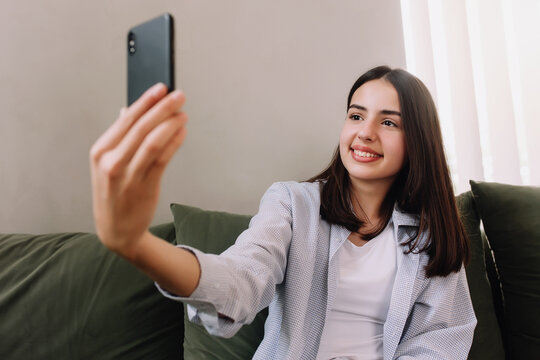 Smiling teenager posing a smile and taking a selfie with smartphone