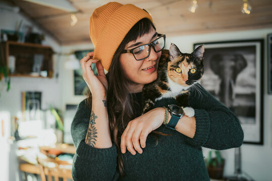 Young woman carrying cat on shoulder