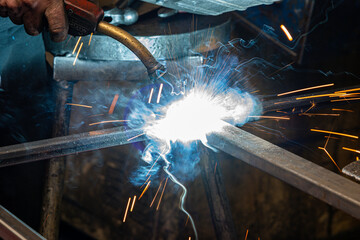 close up photo of the welding of two pieces of steel in a metal workshop, it is seen as a powerful white light comes out and sparks come out while the steel is welded