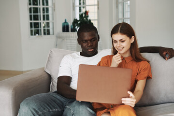 man and woman at home on the couch with a laptop chatting online