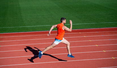 Obraz premium energetic athletic muscular man runner running on racetrack at outdoor stadium, competition