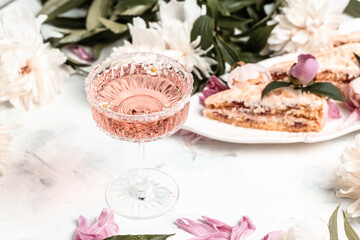 Rose wine glasses, pieces of sweet cake with peonies flowers on white background, top view. Summer drink for party, wine shop or wine tasting concept. banner, menu recipe place for text, top view