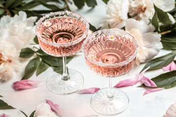 Delicious rose wine in glasses and many peony flowers. Summer celebration, wedding greeting card, invitation concept.