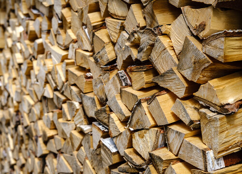 A textured solid background at an angle of birch firewood folded in a dense stack extending into the distance with a copy space.