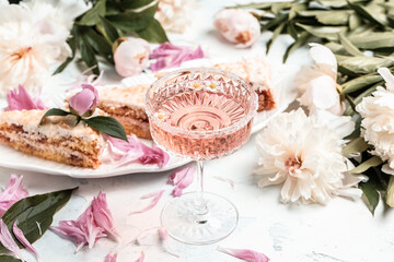 Glass Of White Wine, pieces of sweet cake and Peony Flowers. Summer drink for party, wine shop or...