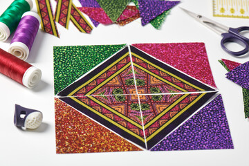 Triangle pieces of fabric laid out in the shape of a patchwork block, sewing and quilting accessories - obrazy, fototapety, plakaty