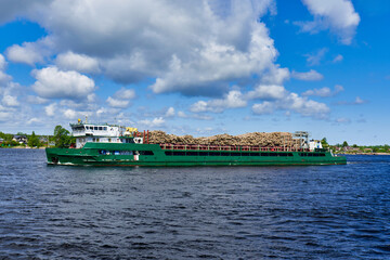 A cargo ship transports sawn trees down the river