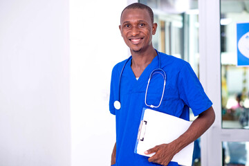 young male doctor holding a blank clipboard smiling.