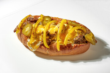 Classic cheese steak with hot jalapeno peppers, beef, cheese. White background. Hard light
