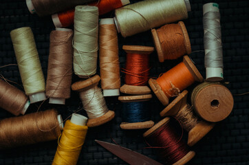 Retro sewing items: tailoring scissors, cutting knife, thimble, wooden thread spools, cushion for...