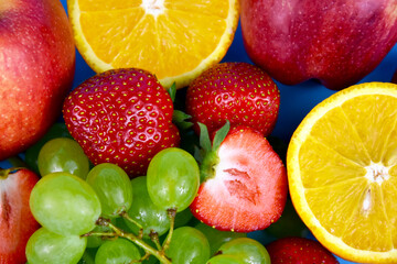 Pile of various fresh fruits close-up stock images. Grapes, strawberries, oranges, apples full frame background stock photo. Mixed many type of juicy fruits images