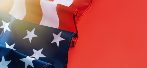 American flag folded in wave on red background with sun glare. Independence day concept, long banner