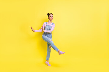 Fototapeta na wymiar Full length photo of funky cute young woman wear denim overall dancing isolated yellow color background