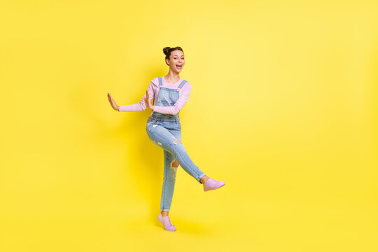 Full length photo of funky cute young woman wear denim overall dancing isolated yellow color background