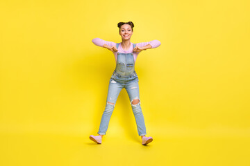 Fototapeta na wymiar Photo of cheerful disco lady stand heels having fun dance wear jeans overall shoes isolated yellow background