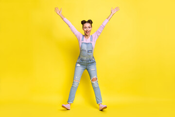 Fototapeta na wymiar Full length photo of pretty adorable young lady dressed jeans overall dancing rising hands arms isolated yellow color background