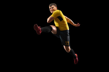 Fototapeta na wymiar Powerful, flying above the field. Young football, soccer player in action, motion isolated on black background .