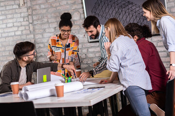 Group of young people discussing architectural designs in the creative office.