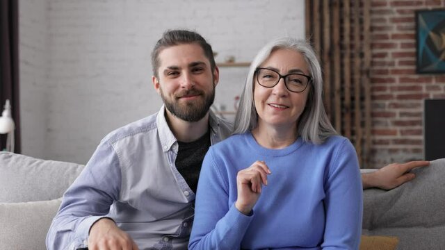Webcam view. Handsome young man with senior mature mother talking to web camera. Communication online with colleagues, relatives, friends. Two generations family.