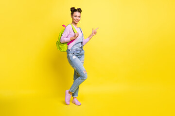 Fototapeta na wymiar Full size photo of optimistic nice brunet lady point empty space wear overall isolated on yellow background