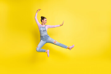 Profile photo of funky lady jump strike leg empty space wear jeans overall footwear isolated yellow background